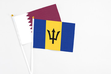 Barbados and Qatar stick flags on white background. High quality fabric, miniature national flag. Peaceful global concept.White floor for copy space.