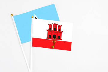 Gibraltar and Saint Lucia stick flags on white background. High quality fabric, miniature national flag. Peaceful global concept.White floor for copy space.