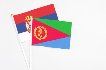 Eritrea and Serbia stick flags on white background. High quality fabric, miniature national flag. Peaceful global concept.White floor for copy space.