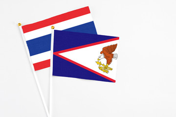 Wall Mural - American Samoa and Thailand stick flags on white background. High quality fabric, miniature national flag. Peaceful global concept.White floor for copy space.