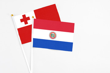 Paraguay and Tonga stick flags on white background. High quality fabric, miniature national flag. Peaceful global concept.White floor for copy space.