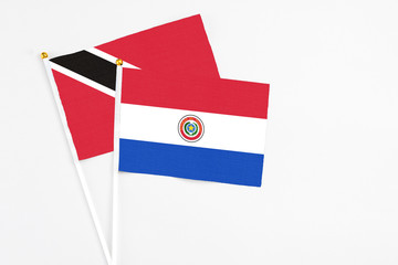 Paraguay and Trinidad And Tobago stick flags on white background. High quality fabric, miniature national flag. Peaceful global concept.White floor for copy space.