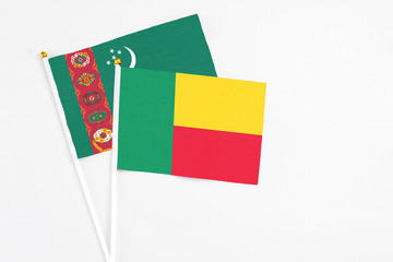 Benin and Turkmenistan stick flags on white background. High quality fabric, miniature national flag. Peaceful global concept.White floor for copy space.