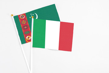 Italy and Turkmenistan stick flags on white background. High quality fabric, miniature national flag. Peaceful global concept.White floor for copy space.