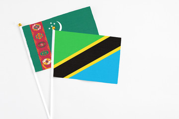 Tanzania and Turkmenistan stick flags on white background. High quality fabric, miniature national flag. Peaceful global concept.White floor for copy space.