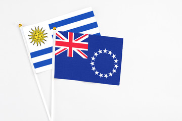 Cook Islands and Uruguay stick flags on white background. High quality fabric, miniature national flag. Peaceful global concept.White floor for copy space.