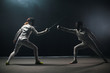A fencing training in the studio - two women in protective suits having a duel