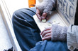 © torsakh - a old man is homeless or beggar sitting or sleeping beside street with cup for request some coin from kindness man and text please help
