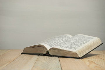 Open  Bible on a old wooden table and white wall background. Religion concept.