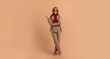 © ClaudiK - Full length studio portrait of young business woman. Full length portrait of smiling attractive businesswoman in suit posing while standing with arms crossed and looking at camera isolated over beige