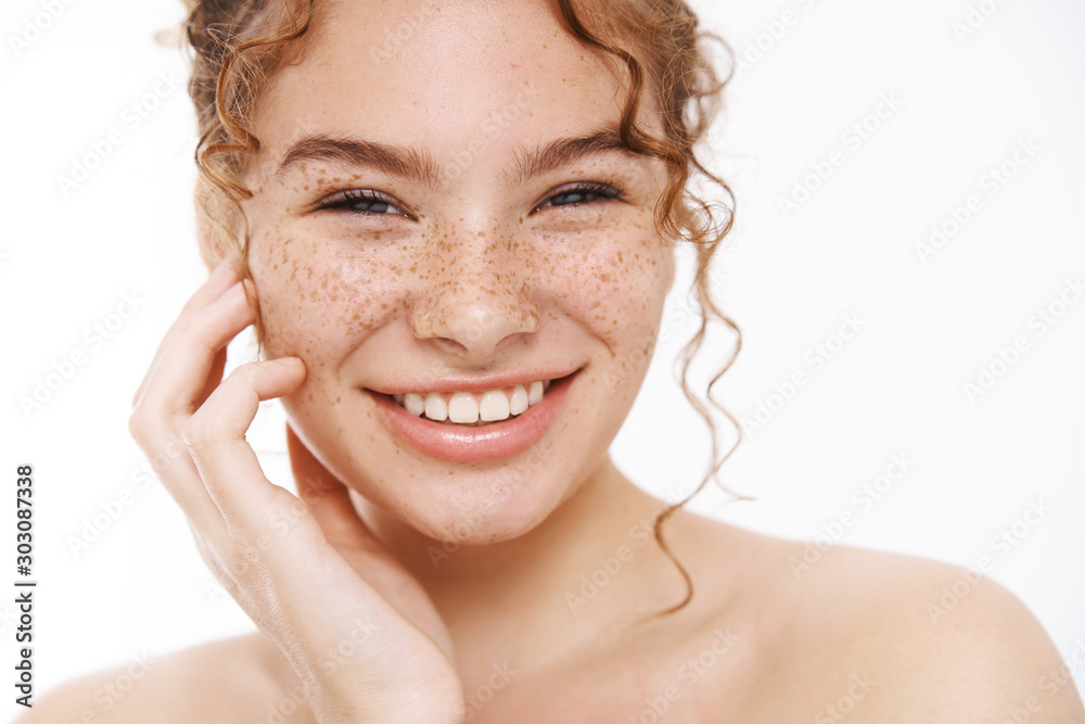 Headshot happy tender redhead girl freckles smiling broadly white teeth standing naked gently touching cheek taking care body showering, applying skincare cosmetics treatment, daily hygiene procedure - obrazy, fototapety, plakaty 