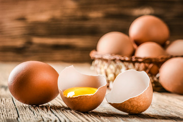 Wall Mural - Fresh brown eggs on wooden table. Broken egg with yolk