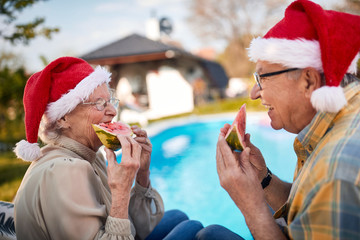  senior couple in Santa hats enjoy on Christmas holiday and eating watermelon