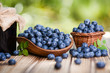 Blueberries in wicker basket on old wooden table. Blueberry jam or marmelade in glass bottle.