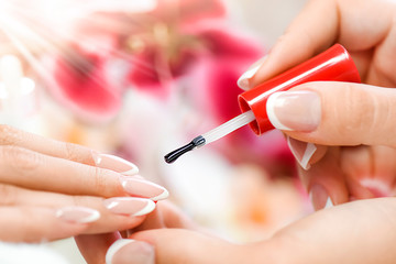 Beautician in luxury salon applying lacquer or varnish gel on nails..Manicure nail paint with brush or artist polish modelation technique.