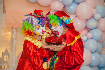 Wall Mural - Funny clowns from the circus. Clown boy and clown girl holding a cake in their hands. The emotions of the holiday.