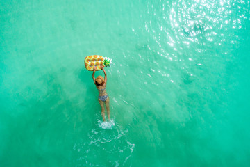 Wall Mural - Aerial view of slim woman swimming on the transparent turquoise sea. Summer seascape with girl, beautiful waves, colorful water. Top view from drone