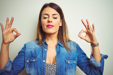 Poster - Young beautiful woman standing over isolated background relax and smiling with eyes closed doing meditation gesture with fingers. Yoga concept.