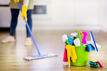 Bucket with cleaning items with modern kitchen and  background. Washing brush and spray set with copy space.