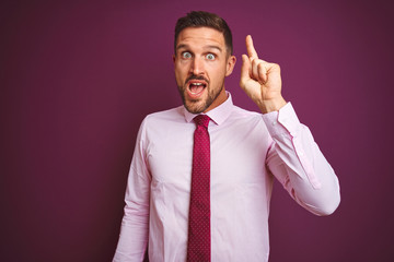 Young business man wearing elegant shirt and tie over purple isolated background pointing finger up with successful idea. Exited and happy. Number one.