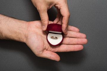 Wall Mural - Open red jewelry box with ring in a male hands. Present. Black background