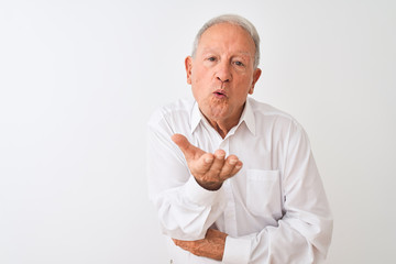 Canvas Print - Senior grey-haired man wearing elegant shirt standing over isolated white background looking at the camera blowing a kiss with hand on air being lovely and sexy. Love expression.