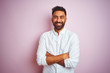 Young indian businessman wearing elegant shirt standing over isolated pink background happy face smiling with crossed arms looking at the camera. Positive person.