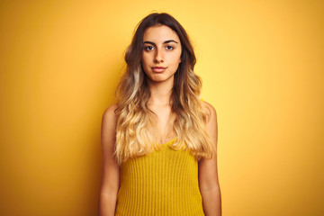 Canvas Print - Young beautiful woman wearing t-shirt over yellow isolated background Relaxed with serious expression on face. Simple and natural looking at the camera.