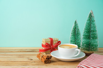 Wall Mural - Christmas holiday background with coffee cup, gift box and pine tree on wooden table.