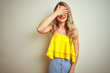 Sticker - Young beautiful woman wearing yellow t-shirt standing over white isolated background smiling and laughing with hand on face covering eyes for surprise. Blind concept.