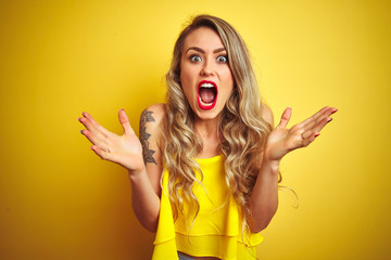 Canvas Print - Young attactive woman wearing t-shirt standing over yellow isolated background celebrating crazy and amazed for success with arms raised and open eyes screaming excited. Winner concept