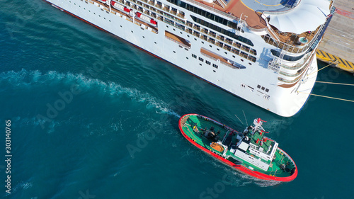 Fotografía Aerial drone photo of tug boat cruising in high speed near cruise liner docked i