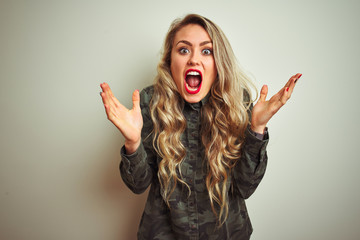 Canvas Print - Young beautiful woman wearing military camouflage shirt over white isolated background celebrating crazy and amazed for success with arms raised and open eyes screaming excited. Winner concept