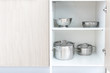 Storage of steel metal pans and other kitchenware, cookware utensils in cupboard of modern kitchen, copy space