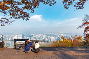 Two women looking at the autumn foliage and view of Seoul city from Namsan Tower area.