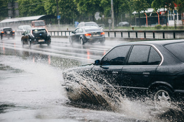 Ukraine. Kiev - 05,12,2019 Spraying water from the wheels of a vehicle moving on a wet city asphalt road. The wet wheel of a car moves at a speed along a puddle on a flooded city road during rain.