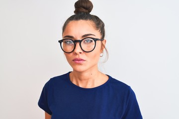 Wall Mural - Beautiful woman with bun wearing blue t-shirt and glasses over isolated white background with a confident expression on smart face thinking serious