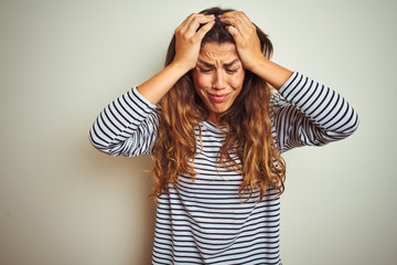 Wall Mural - Young beautiful woman wearing stripes t-shirt over white isolated background suffering from headache desperate and stressed because pain and migraine. Hands on head.