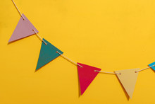 Bright Multi-colored Paper Garland Flags On A Yellow Background. Paper Fun Decorations For Birthday. Props For Photo Shoot Booth Decoration For Holiday Festival Wedding Party.