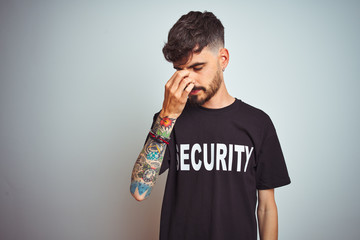 Sticker - Young safeguard man with tattoo wering security uniform over isolated white background tired rubbing nose and eyes feeling fatigue and headache. Stress and frustration concept.