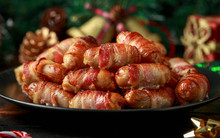 Christmas Pigs In Blankets, Sausages Wrapped In Bacon With Decoration, Gifts, Green Tree Branch On Wooden Rustic Table