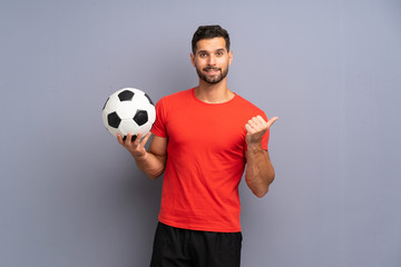 Handsome young football player man over isolated white wall pointing to the side to present a product