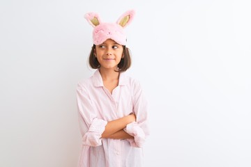 Sticker - Beautiful child girl wearing sleep mask and pajama standing over isolated white background smiling looking to the side and staring away thinking.