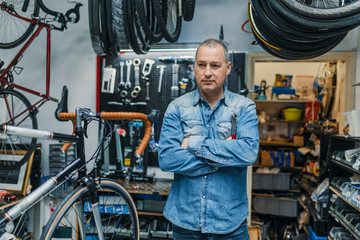 stylish bicycle mechanic standing in his workshop.