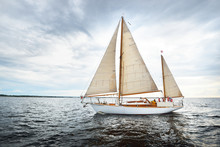Vintage Wooden Two Mast Yacht (yawl) Sailing In A Open Sea On A Clear Day. Waves And White Clouds
