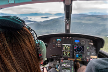 woman is in the helicopter in alaska. they are flying over the mountains and glacier. this is a sigh