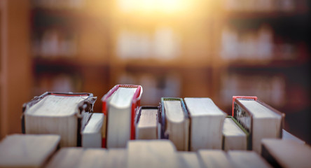 Poster - Stack of books in the library and blur bookshelf background
