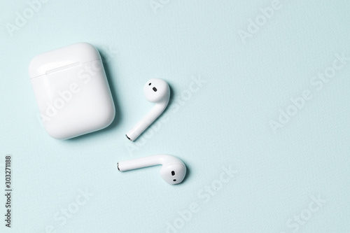 Fotografía Wireless headphones on a blue background with place for text.