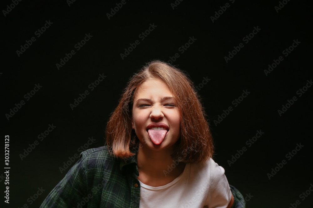 Grimacing teenage girl on dark background