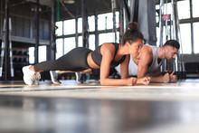 Portrait Of Beautiful Young Sports Couple On A Plank Position.